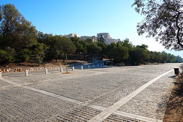 The wide paved Dionysiou Areopagitou promenade lined with trees, with the Acropolis in the distance