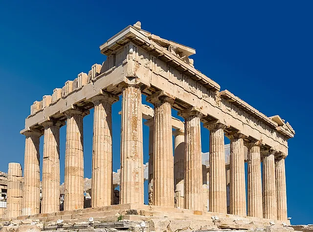 The Parthenon seen at an angle, its Doric columns and the corner of the pediment against a deep blue sky